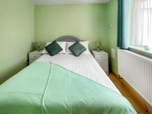 a bedroom with a large bed with green sheets and pillows at Parade - Uk49713 in Greatstone