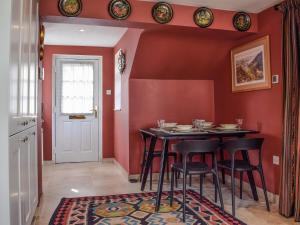 une salle à manger avec des murs rouges, une table et des chaises dans l'établissement Lomond Cottage, à Garsington