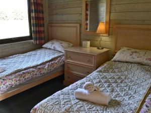 ein Schlafzimmer mit zwei Betten mit einem Teddybär auf einem Kissen in der Unterkunft Hartland Forest Golf & Leisure in Woolfardisworthy + 6 Fotos