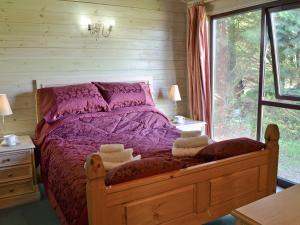 ein Schlafzimmer mit einem Bett mit violetter Bettwäsche und einem Fenster in der Unterkunft Hartland Forest Golf & Leisure in Woolfardisworthy