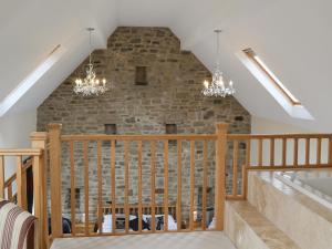 a staircase with chandeliers and a brick wall at The Farm House in Wolsingham