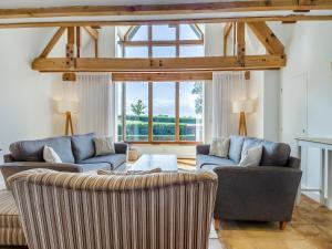 a living room with two couches and a large window at Wittle Cottage in Quidenham
