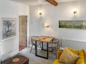 a living room with a table and a yellow couch at Wisteria Cottage in Harrogate