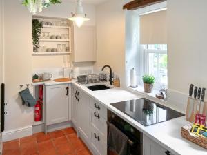 a kitchen with white cabinets and a sink at Wisteria Cottage in Harrogate