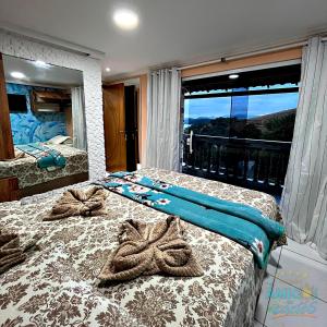 a bedroom with two beds and a large window at Pousada Amigos do Caetés in Angra dos Reis