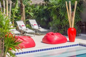 dos jarrones rojos sentados en una mesa junto a una piscina en The White Cottage en Bophut 