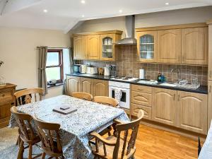 a kitchen with a table and wooden cabinets at 4 Swallowholm Cottage in Richmond