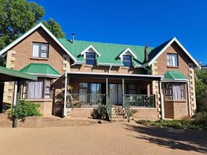 a large brick house with a green roof at Clarens Mountain Sage Holiday House in Clarens