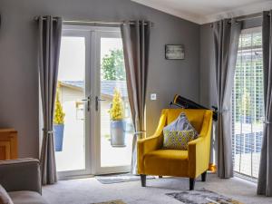 a yellow chair in a living room with sliding glass doors at Seagrass Lodge in Carnguwch
