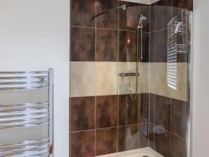 a bathroom with a shower with brown tiles at Seagrass Lodge in Carnguwch +2 photos