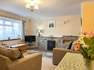 a living room with a fireplace and a tv at Eastry Cottage in Castleton