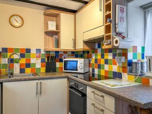 a kitchen with a sink and a microwave at Eastry Cottage in Castleton