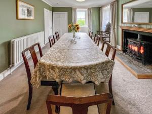 a dining room with a table with chairs and a fireplace at Rottal Farmhouse in Millton of Clova