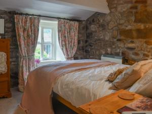 a bedroom with a bed and a stone wall at Horseshoe Cottage in Starbotton