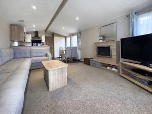 a living room with a couch and a flat screen tv at Unit 44 in Weybourne