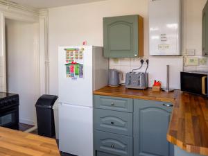 eine Küche mit blauen Schränken und einem weißen Kühlschrank in der Unterkunft Cosy Cottage in Manningtree