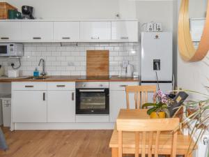 a kitchen with white appliances and a wooden table at Trinity Bee in Ventnor