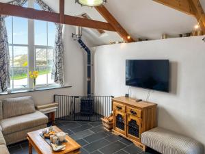 Una sala de estar con un televisor de pantalla plana en una pared. en The Milking Parlour, en St Ives