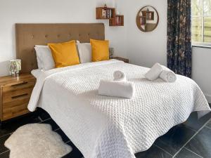 Un dormitorio con una gran cama blanca con toallas. en The Milking Parlour, en St Ives 10 fotos más