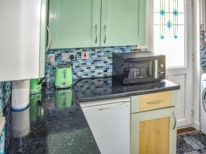 eine Küche mit grünen Schränken und einer Mikrowelle in der Unterkunft Surfers Halt in Woolacombe