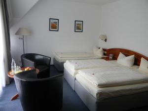 a hotel room with two beds and a table and chairs at Hotel Stadt Norderstedt in Norderstedt +11 photos