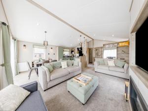 a living room with two couches and a tv at Hillfort Lodge in Llanrhystyd