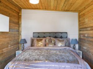 a bedroom with a large bed with wooden walls at Alpaca Lodge in Acton