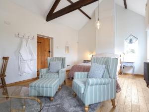 - une chambre avec deux chaises bleues et un lit dans l'établissement Blossom Cottage, à Lydney
