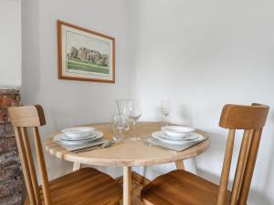 une table en bois avec des assiettes et des verres dans l'établissement Blossom Cottage, à Lydney 14 autres photos
