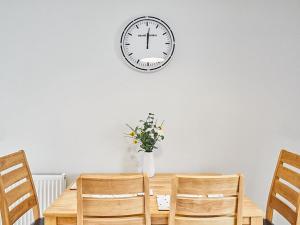 a dining room table with a clock on the wall at Aynsley Mews in Consett
