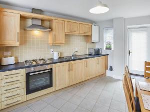 a kitchen with wooden cabinets and a sink at Aynsley Mews in Consett +19 photos