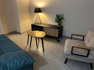 ein Wohnzimmer mit einer Couch und einem Tisch und einem Stuhl in der Unterkunft Meublé Voltour dans la Villa Denise in Vals-les-Bains