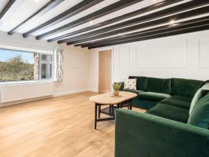 a living room with a green couch and a table at Rigg Farm Cottage in Stainsacre