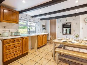 a kitchen with wooden cabinets and a table and chairs at Rigg Farm Cottage in Stainsacre