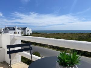 a balcony with a table and a view of the ocean at Namaste - Sea-facing 4 sleeper Holiday Home in Paternoster
