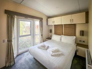 een slaapkamer met een groot wit bed met handdoeken erop bij Aquila - Uk49467 in Morpeth