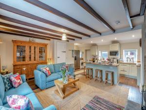 un soggiorno con un divano blu e una cucina di The Old Cottage a Beadnell