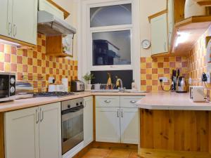 Una cocina con gabinetes blancos y una ventana. en Chestney House, en Hunstanton