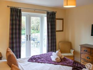 a bedroom with a bed and a sliding glass door at Roslin Chapel Lodge - Uk49194 in Roslin