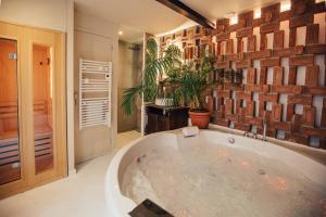 a large bath tub in a bathroom with a brick wall at La Douce Lille Croix Spa Privatif by Moment Parenthèse in Croix +34 photos