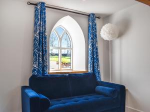 a blue couch in a room with a window at Lavender Cottage -Uk49209 in Jacobstowe