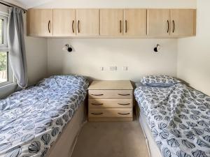 2 Betten in einem kleinen Schlafzimmer mit Schränken in der Unterkunft The Lodge in Chapel Saint Leonards