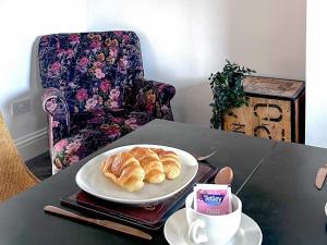 einen Teller Croissants und eine Tasse Kaffee auf dem Tisch in der Unterkunft Follonsby Foal Cottage in Hebburn-on-Tyne