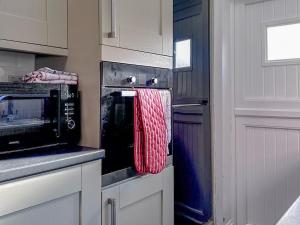 eine Küche mit einem roten Handtuch, das von einer Mikrowelle hängt in der Unterkunft Follonsby Foal Cottage in Hebburn-on-Tyne