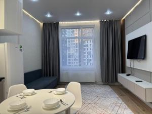a living room with a table and a tv at Buqar Jyrau Exclusive Business Residental Complex in Astana