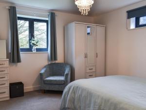 a bedroom with a bed and a chair and a dresser at St Andrews Place in Stratton