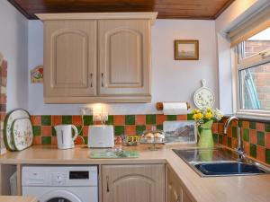 a kitchen with wooden cabinets and a sink at Kathys Cottage in Kings Lynn