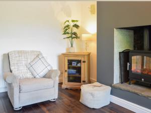 a living room with a chair and a fireplace at Doorstones Cottage in Moorside +14 photos
