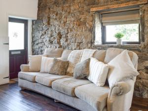 a couch in a living room with a stone wall at Doorstones Cottage in Moorside