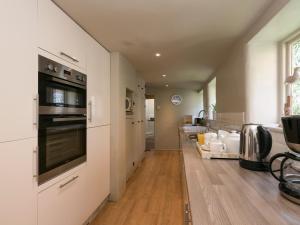 a kitchen with white cabinets and a stove top oven at Dell Cottage in Mundesley